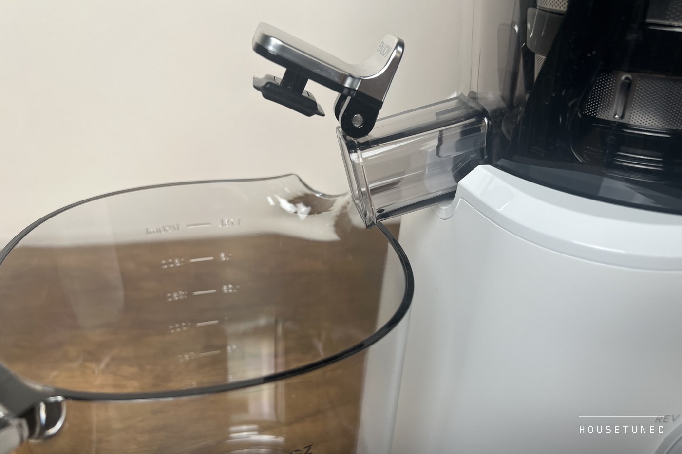 Close view of the J2's juice outlet with its metal cap flipped open above the clear jug