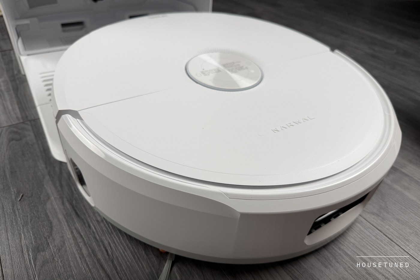 A low, close view of the Freo 20 Edge on a grey wood-effect floor, its side brush at the front edge