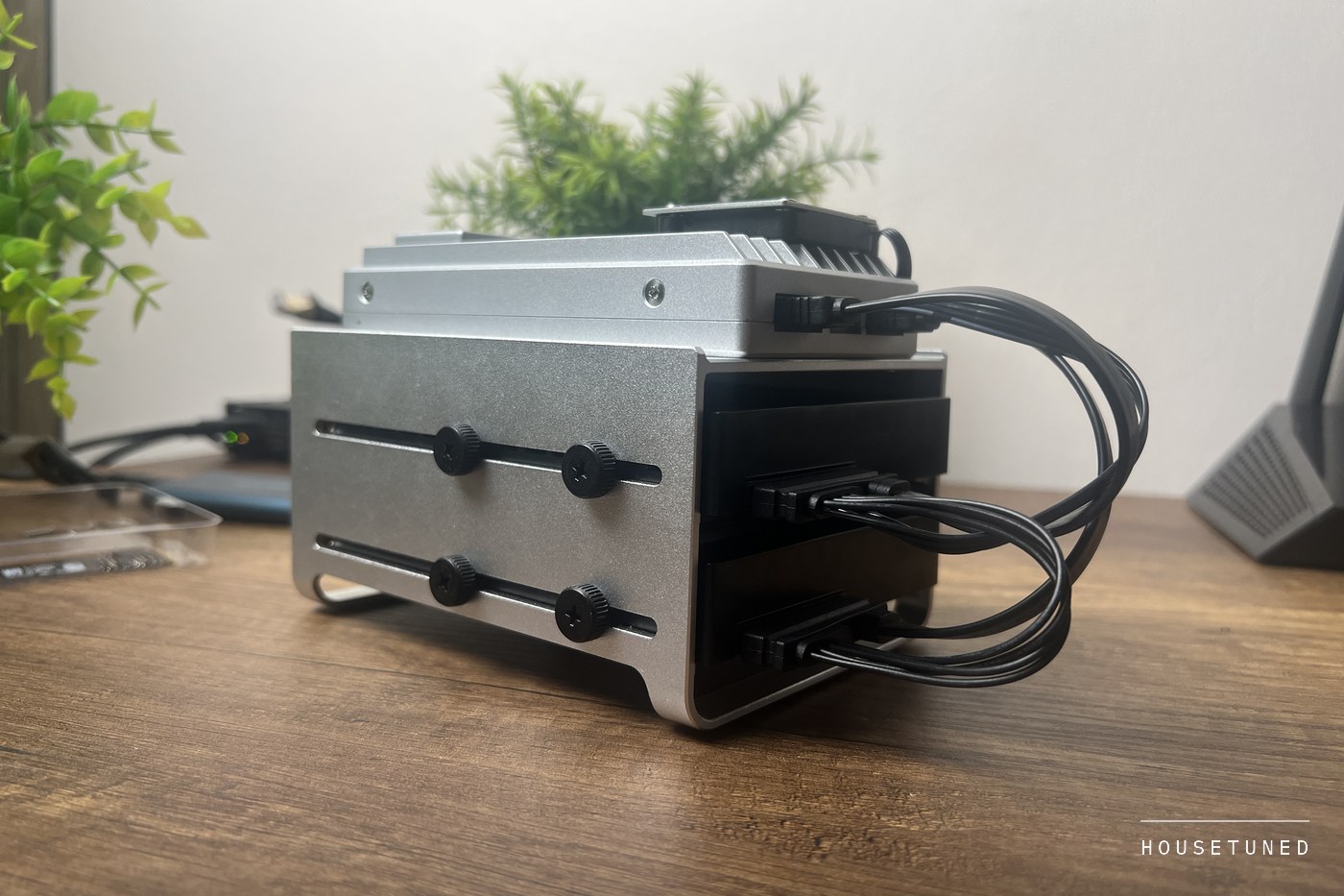 The side of the two bay drive tray with its thumbscrews, and SATA cables curving from the drives up into the back of the board