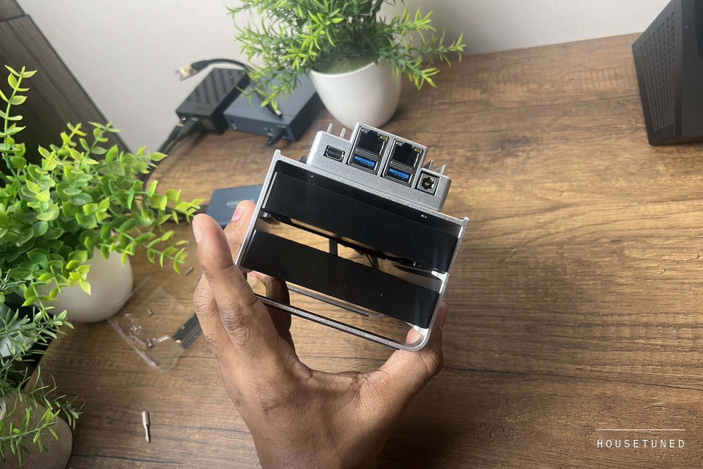 The front edge of the board held in one hand, showing the mini DisplayPort, both ethernet sockets, two USB ports and the power jack