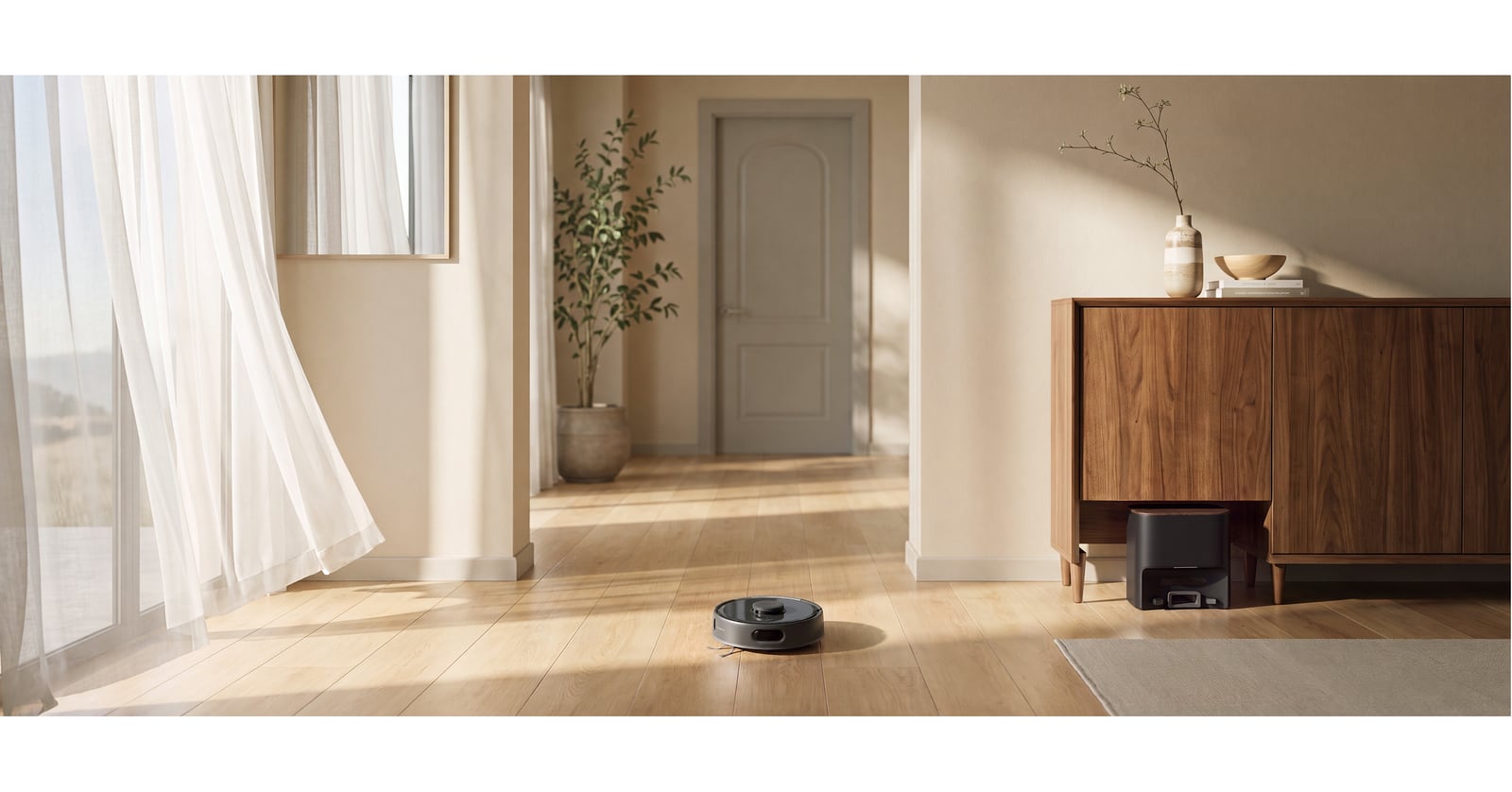 A black robot vacuum on a wood floor beside its auto-empty dock beneath a wooden sideboard.