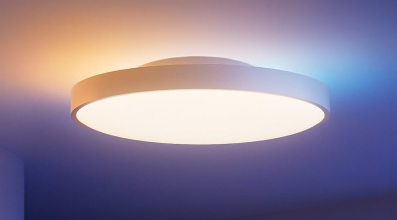 Round S1 ceiling light with a white illuminated diffuser and colored ambient light on the ceiling.